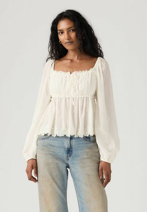 Witte, lichtgewicht blouse met opgepofte lange mouwen, een geplooide lijfje, en bloemenborduursels. Zesdaagse zoom, gecombineerd met lichtgewassen denim jeans.