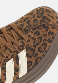 Baskets marron à imprimé léopard avec lacets marron, bandes latérales blanches et semelle épaisse en caoutchouc marron foncé.