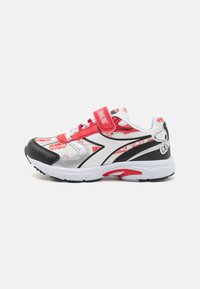 Zapatillas deportivas en blanco y negro con acentos rojos. Presentan un diseño estampado con gráficos de "Peanuts" y una correa de Velcro para el cierre.