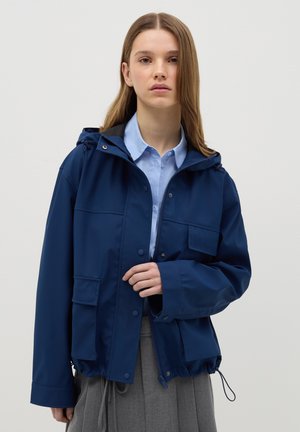 Giacca impermeabile blu navy con cappuccio, chiusura a scatto e zip, due tasche frontali, orlo regolabile con cordino e vestibilità comoda.