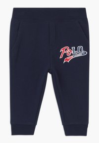 Pantalones jogger de algodón azul marino con cintura elástica, bolsillos laterales y un logo rojo y blanco de "Polo Ralph Lauren" en el muslo izquierdo.