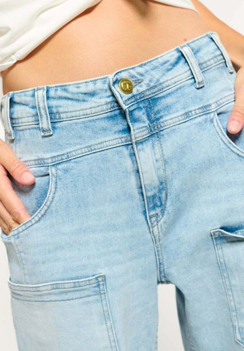 Lichtblauwe denim cargobroek met een hoge taille, een gouden knoop, twee voorzakken en een relaxed fit. Textuur lijkt zacht en enigszins vervaagd.