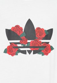 Μαύρο λογότυπο τριφυλλιού με κόκκινα τριαντάφυλλα και πράσινα φύλλα σε λευκό φόντο. Το γραφικό σχέδιο χαρακτηρίζεται από έντονες γραμμές κα�ι ζωντανά χρώματα.