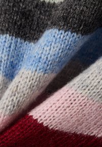 Tissu en laine tricoté avec des rayures diagonales gris, bleu clair, rose pâle et rouge, présentant une surface douce et texturée.