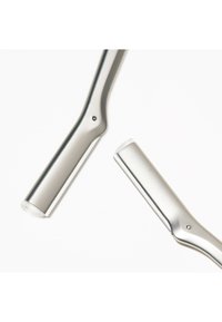 Sølvfarvede barberskrabere i metal med sammenklappelige håndtag og små beskyttende kamme, på hvid baggrund.