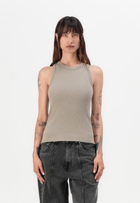 Grå ribbestrikket tanktop med høy hals og uten ermer, parret med m�ørkegrå vide jeans. Jevn tekstur og tettsittende silhuett.