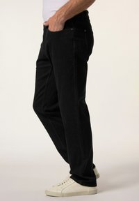 Schwarze Denim-Jeans mit geradem Bein, ausgestattet mit Fronttaschen und einem Knopfverschluss, kombiniert mit weißen Sneakers.