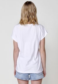 T-shirt en coton blanc à manches courtes, coupe décontractée, col rond et texture lisse, associé à un short en denim bleu clair.