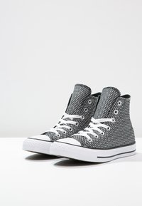 Sneakers alta in tessuto con motivo a diamante bianco e nero, lacci bianchi e suola in gomma bianca con rifiniture nere.