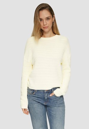 Lichtgele gebreide trui met een gestreept textuurpatroon, ronde halslijn en lange mouwen, gecombineerd met blauwe jeans.