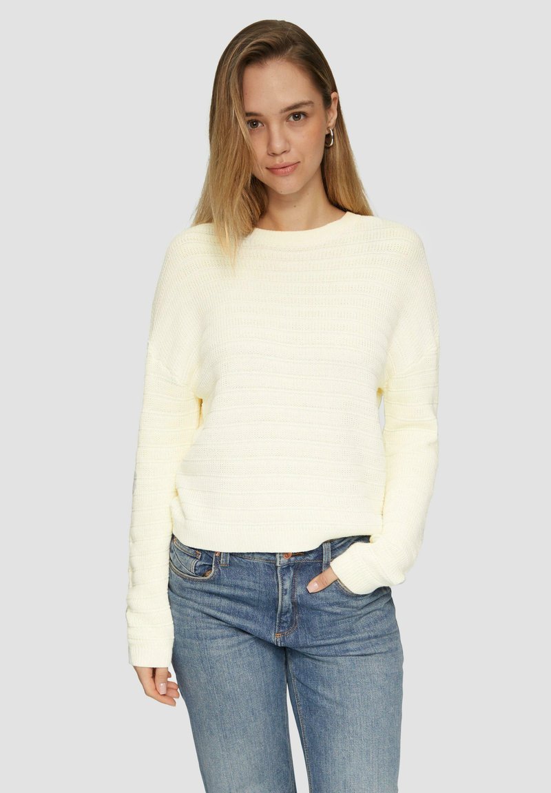 Pull en maille jaune clair avec un motif rayé texturé, encolure ronde et manches longues, associé à un jean bleu.