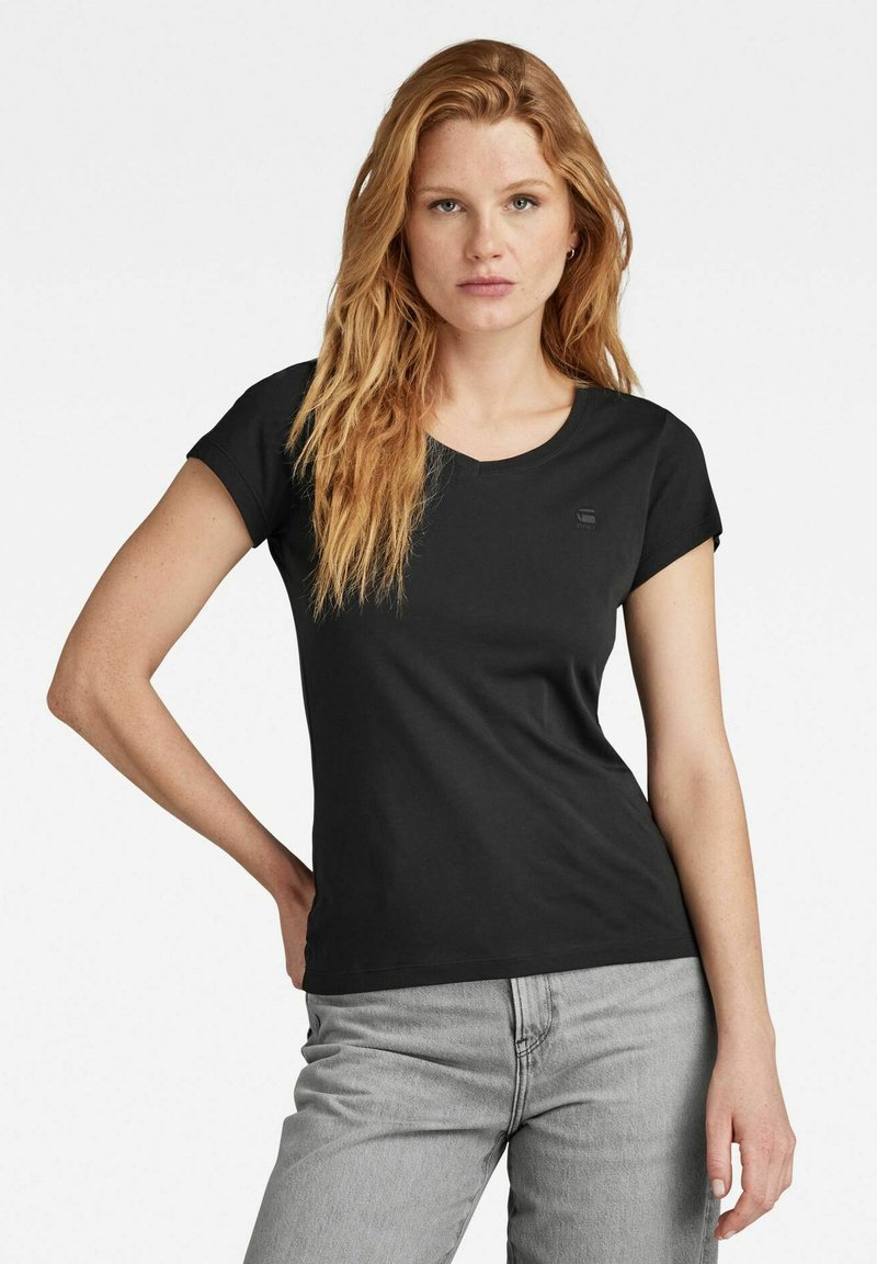 Black cotton t-shirt with a round neckline and short sleeves, featuring a subtle logo detail on the chest, displayed with gray jeans.