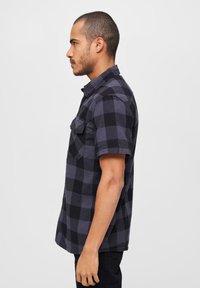 Korte mouw flanellen shirt in zwart en donkergrijs ruitpatroon, met twee borstzakken en een klassieke kraag, gemaakt van zachte katoen.