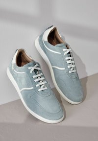 Baskets en suède bleu clair avec des accents et des lacets blancs. Détails perforés sur les orteils et une semelle blanche texturée.