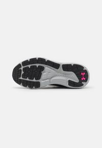 Suola di scarpa sportiva nera con un design testurizzato, caratterizzata da una intersuola in gomma grigia e un accento del logo Under Armour in rosa.