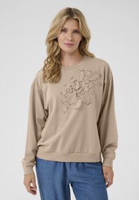 Felpa beige con maniche lunghe e scollatura a girocollo, caratterizzata da un design in applique floreale testurizzato sul davanti e polsini a costine.