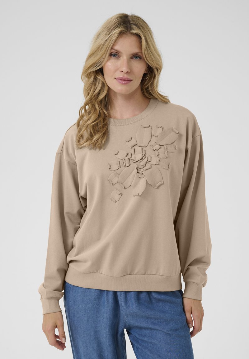 Felpa beige con maniche lunghe e scollatura a girocollo, caratterizzata da un design in applique floreale testurizzato sul davanti e polsini a costine.