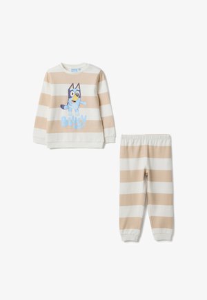 Sweatshirt à rayures beige et blanches avec un personnage de dessin animé, accompagné d'un pantalon assorti. Matière en mélange de coton. Manches avec poignets côtelés et taille élastique.