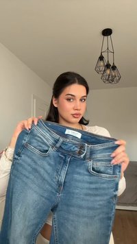 Wyblakłe niebieskie dżinsy o prostym kroju, z paskiem, dwoma przednimi kieszeniami i zapięciem na guzik. Teksturowany materiał dżinsowy.