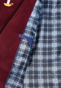 Burgundy fabric with a smooth texture, featuring a candle motif. Lined with blue fabric patterned in black and white checks, with a blue accent.
