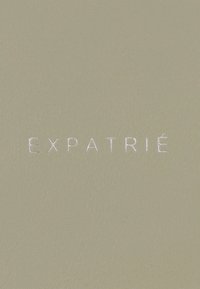 Parola in rilievo "EXPATRIÉ" in lettere maiuscole bianche su una superficie di pelle beige liscia.