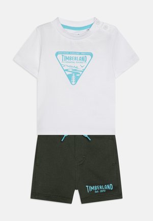 Bela majica s plavim Timberland grafikom in zelenimi kratkimi hlačami s plavim vrvico in znamko. Bombažna tkanina, kratki rokavi, sproščen stil.