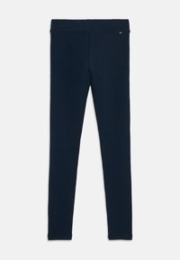 Marina blå leggings i mjukt, stretchigt tyg. Har en bred midjeband och en liten logotypdetalj på toppen. Slät textur.