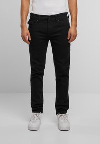 Jeans negre din denim cu croi slim, cinci buzunare, detalii subtile de cusătură și talie medie. Asortați cu adidași albi.