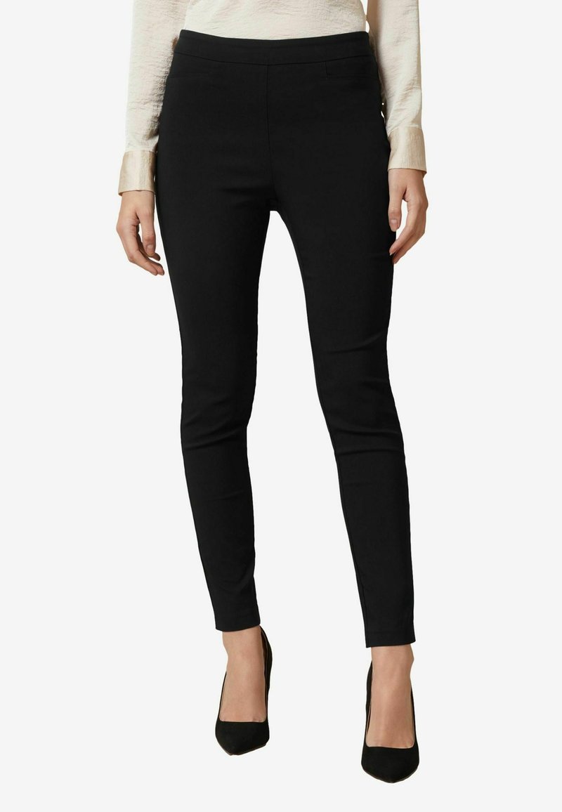 Černé kalhoty na míru se slim fit střihem, vyrobené z elastického materiálu. Mají hladký povrch a střední pas. Žádné viditelné kovové prvky.