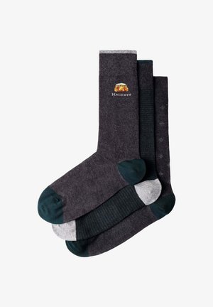 Tres pares de calcetines para hombre en gris oscuro con diferentes colores en los dedos y el talón, un par presenta un pequeño logo bordado con el texto "Hackett".