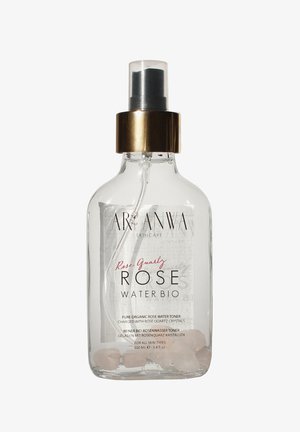 Flacon pulvérisateur en verre transparent de tonique bio à l'eau de rose Arganwa Rose Quartz avec des cristaux de quartz rose à l'intérieur et un col doré sur la pompe.