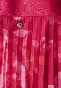 Rosa plissierter Rock mit einem strukturierten Bund mit geprägtem Schriftzug, floralen Mustern und einer metallischen Akzentuierung in der Taille.