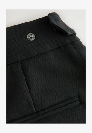 Čierny textilný odev s klopou, strieborným cvokom a plochými vreckami s čistým prešívaním. Hladká štruktúra s prešívaným dizajnom.