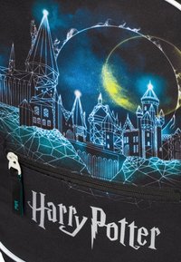 Batoh s černým pozadím a modro-zelenou noční oblohou. Detailní geometrický design hradu s textem "Harry Potter" v bílé barvě.