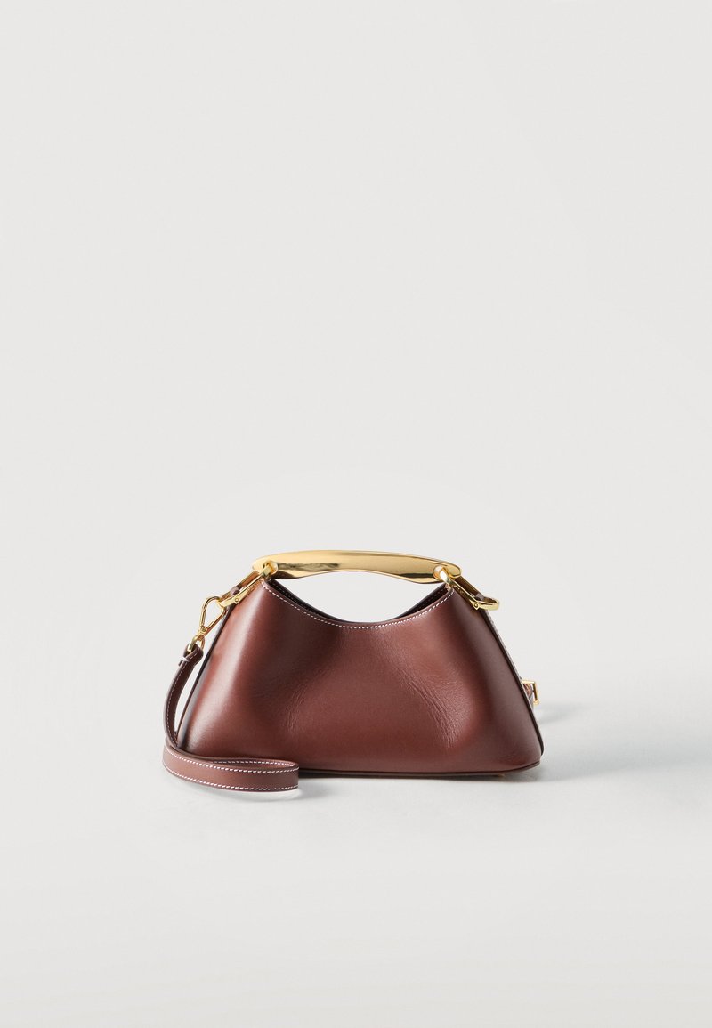 Καφέ δερμάτινη τσάντα χειρός με χρυσή μεταλλική λαβή στην κορυφή και αποσπώμενο ιμάντα ώμου σε λευκό φόντο.