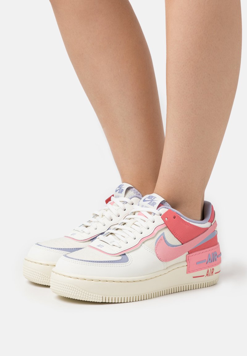Sneakers Nike Air Force 1 w kolorze białym, różowym i jasnofioletowym, z teksturowaną skórzaną cholewką, gumową podeszwą oraz wyraźnymi akcentami "AIR".