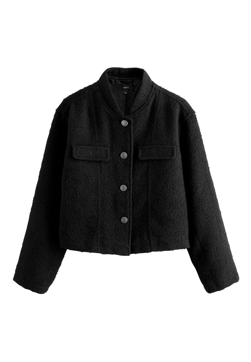 Giacca corta nera in tessuto strutturato. Presenta un colletto rotondo, chiusura frontale con bottoni, due tasche sul petto e maniche lunghe.