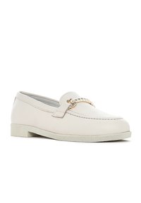Mocassino in pelle beige chiaro con accentuazione in catena dorata, suola piatta con texture e dettagli cuciti lungo la parte superiore.