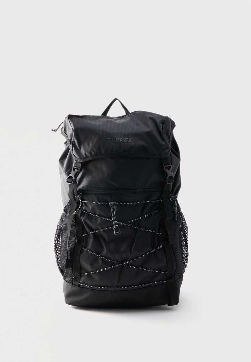 Μαύρο σακίδιο Terrex με επάνω καπάκι, μπροστινή τσέπη με φερμουάρ, ρυθμιζόμενους ιμάντες και λεπτομέρεια με ελαστικό κορδόνι, στέκεται σε απλό φόντο.