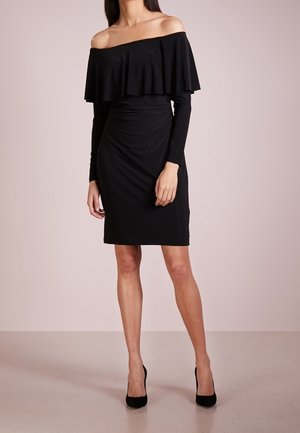 Zwarte off-shoulder jurk met gerimpelde korte mouwen, aansluitend lijfje en knie-lange zoom. Gladde textuur en effen kleur. Bijpassende zwarte hakken.