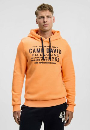 Oranger Hoodie aus weichem Stoff mit einem Frontdruck mit Text. Er verfügt über eine Kapuze mit Kordelzug sowie gerippte Bündchen und Saum.
