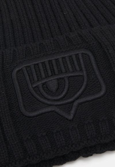 Beanie in maglia nera con un motivo a coste testurizzato e un design del logo in rilievo che assomiglia a un occhio all'interno di una nuvola di dialogo.