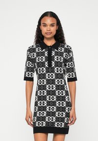 Vestido polo em preto e branco com padrão, com mangas curtas, apresentando colarinho e botões frontais, feito de material de malha texturizada.