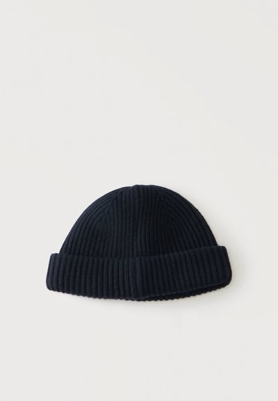Bonnet en tricot côtelé noir avec revers replié sur un fond clair uni.