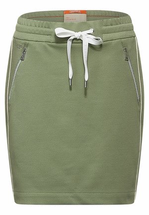 Jupe crayon en tricot vert olive avec cordon blanc, poches latérales zippées et une petite étiquette orange au dos de la ceinture.