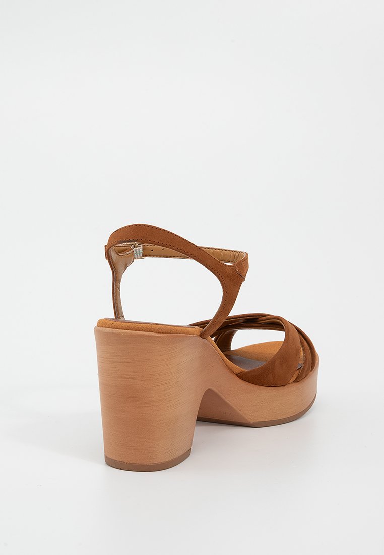 Sandale à talon haut en suède marron avec un talon bloc en bois, bout ouvert et bride de cheville, présentant un design supérieur entrecroisé.