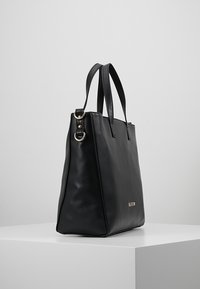 Svart läderhandväska med en strukturerad finish, utrustad med två axelremmar och guldfärgade detaljer på sidan.