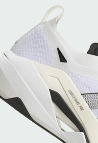 Sneaker da uomo in tessuto bianco testurizzato, con accenti neri, design leggero e una suola in gomma distintiva.