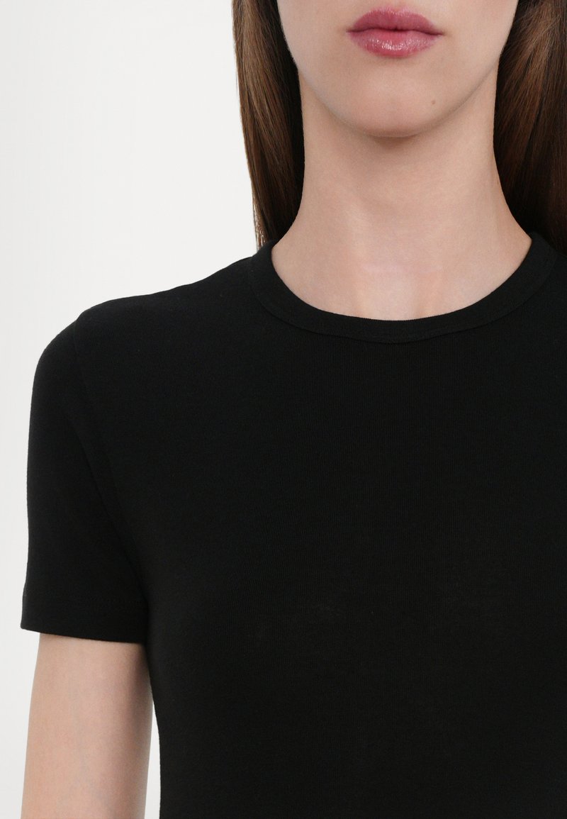 T-shirt nera a maniche corte, design aderente, texture liscia, scollatura rotonda, stile minimalista, senza motivi visibili o decorazioni.