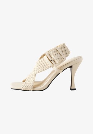 Beige højhælede sandal med design af vævede remme, firkantet tå og justerbar spænde. Har en slank hæl og glat tekstur.